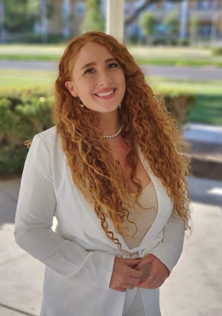 jenni cole wearing a white jacket smiling with her long red hair